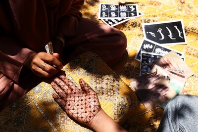 Henna artist Azra Khamissa paints a woman’s hand at her residence in Dubai. Reuters