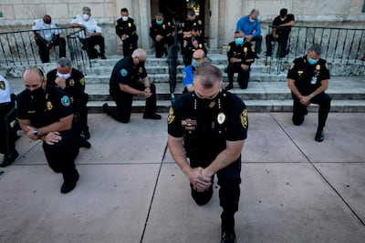 Police officers kneel during a rally in Florida on May 30 in response to the killing of George Floyd. AFP