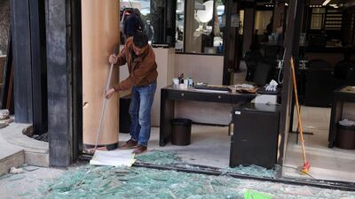 A worker clears up the shattered glass windows of a local Credit Libanais SAL bank branch in Beirut on Wednesday. Bloomberg