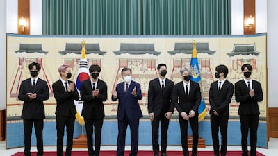This picture taken on September 14, 2021 shows South Korean President Moon Jae-in (4th L) posing with members of K-pop sensation BTS as they receive diplomatic passports for a UN session as presidential special envoys at the presidential Blue House in Seoul. (Photo by - / YONHAP / AFP) / - South Korea OUT / REPUBLIC OF KOREA OUT NO ARCHIVES RESTRICTED TO SUBSCRIPTION USE