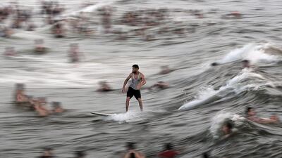 A Palestinian man surf as people enjoy the hot weather at a beach in Gaza city. Mohammed Saber / EPA