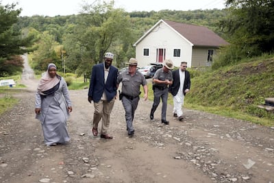 Tahirah Clark, left, and Faruq Baqi walk with New York State Police Capt Scott Heggelke, center, in the Muslim enclave of Islamberg. AP