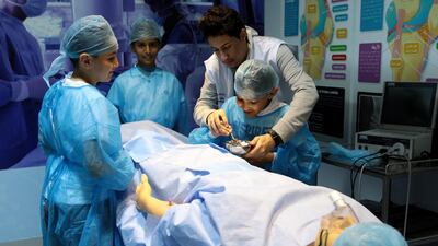 (L-R) Khalid Al Khushashi, 11, Abdulla Ghanem, 11, and Ali Al Khushashi, 9, take part in the OR surgery activity with science communicator Ammar Alhat. Christopher Pike / The National
