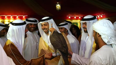Sheikh Mansour bin Zayed, centre, Deputy Prime Minister and Minister of Presidential Affairs, smiles as he is shown a hunting falcon during the opening of the Abu Dhabi International Hunting and Equestrian Exhibition in 2004. AFP