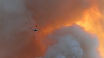 A firefighting helicopter carries water over a forest fire that broke out Datca, south-west Turkey. AFP