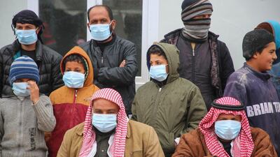 Displaced Syrians, some wearing protective masks, listen as medics hold an awareness campaign on how to be protected against the novel coronavirus pandemic. AFP