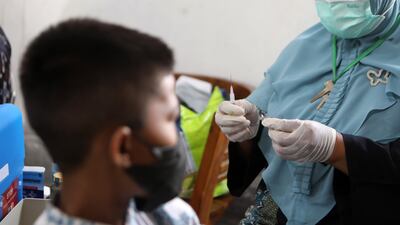 An elementary school student looks on as a healthcare worker prepares a dose of Covid-19 vaccine in Banda Aceh, Indonesia. EPA