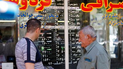 Iranians check the currency rate in Tehran. The rial has tumbled to above 100,000 to the dollar. EPA