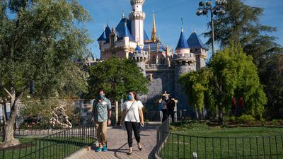 Guests wearing protective masks walk past Sleeping Beauty Castle during the reopening of the Disneyland theme park in Anaheim, California, US, on Friday, April 30, 2021. Bloomberg