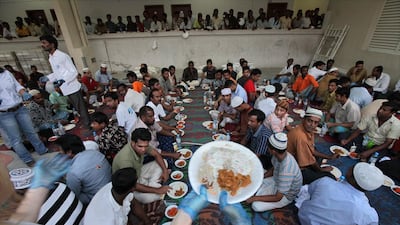 Volunteers pass plates of food for workers in a labour camp in Al Quoz 2 in Ramadan. Jaime Puebla / The National