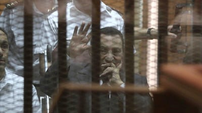 Egypt's deposed president Hosni Mubarak waves from behind the accused cage during his trial on May 21, 2014 in Cairo. An Egyptian court sentenced Mubarak to three years in prison on corruption charges, in one of two trials after the 2011 uprising that ended his rule. Hassan Mohamed/AFP Photo