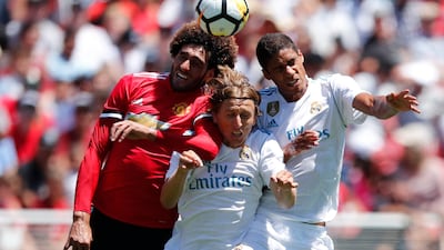 Manchester United midfielder Marouane Fellaini, left, and Real Madrid midfielder Luka Modric, centre, and Real Madrid defender Raphael Varane in action. John G Mabanglo / EPA
