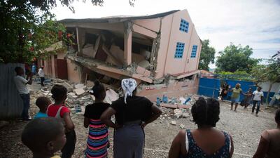 Residents look at a collapsed school destroyed by a magnitude 5.9 earthquake in Haiti. AP