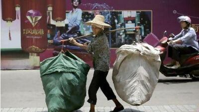 An elderly Chinese woman carrying bags walks down the street in Liuzhou, China.