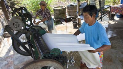 Somporn Klaharn, and his wife Thongshin work together in their small processing plant pressing sheets of rubber in Rayong, Thailand. Paula Bronstein / Getty Images