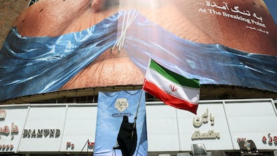 A woman holds an Iranian flag in front of an anti-US billboard referring to US President Donald Trump and the Strait of Hormuz in Tehran. EPA