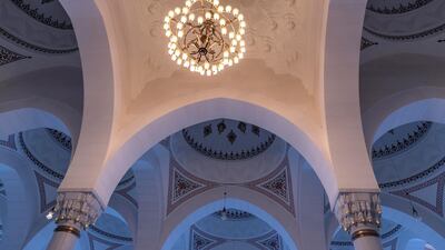 The mosque’s main prayer hall has arched windows with stained glass, walls decorated with verses from the Quran