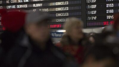 Commuters board a train near the departures board at Penn Station in New York on January 27, 2015. Amtrak cancelled all trains to Boston for the day and ran a modified schedule between New York and Washington DC following a night of snowfall in the north-east region. Andrew Kelly/EPA