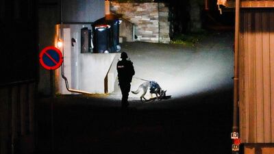 A police officer uses a sniffer dog at the scene. AFP