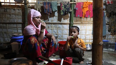 Minara Akhter, a divorced Rohingya refugee, with her son Mohammad Abdullah, seven, eat at the makeshift camp in Kutupalong