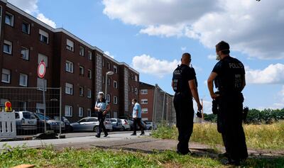 Police officers stand outsidethe residential homes of slaughterhouse employees who have been placed under strict quarantine. AFP