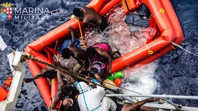 Rescuers help refugees board an Italian navy ship in the Mediterranean Sea on Friday, after the boat they were aboard sunk. Raffaele Martino/Marina Militare via AP Photo