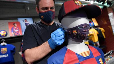 An employee places a mask with the logo of FC Barcelona on a mannequin at the FC Barcelona store. AFP