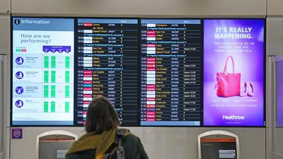 A passenger looks at a departures board at London Heathrow Airport's T3. PA
