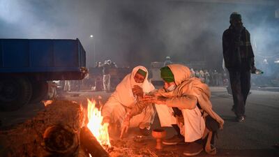 Farmers warm up around a bonfire under a bridge near a police road block stopping them from marching to New Delhi to protest against the central government's recent agricultural reforms. AFP