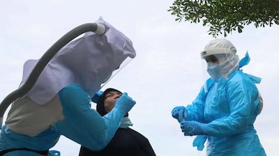 Medical officers in personal protective equipment conduct a Covid-19 coronavirus test on a woman in southern Thailand's Yala province, amid an increase in active case numbers in the region. AFP