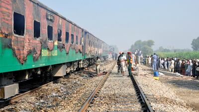 People and rescue workers gather at the place where a fire broke out in a passenger train and destroyed three carriages near the town of Rahim Yar Khan, Pakistan. Reuters