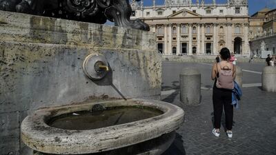 A woman stands near a fountain that has been switched off in St Peter's Square, in Vatican city, on July 25, 2017. Andreas Solaro / AFP