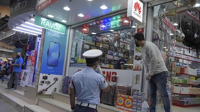 A Bahraini police officer instructs a foreign shop vendor to wear his protective mask amid the Covid-19 pandemic in the old market place of the Bahraini capital Manama. AFP