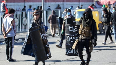 Iraqi protesters with makeshift protective gear walk by following clashes with security forces during an anti-government demonstration in Al-Khilani square in the capital Baghdad. AFP
