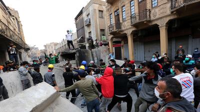 Iraqi protesters try to pull down a concret block which was used by Iraqi police forces to close Al Rasheed street, near the headquarters of the Central Bank of Iraq in central Baghdad. EPA
