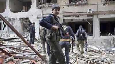 A Free Syrian Army fighter in front of a building destroyed during clashes in the Haresta neighbourhood of Damascus.