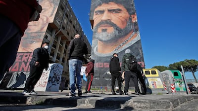 People gather beneath a giant mural of Diego Maradona in Naples. Reuters