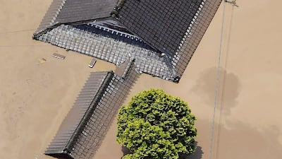 Residents are stranded on the rooftop of a house submerged in muddy waters that gushed out from the Kuma River in Hitoyoshi, Kumamoto prefecture. Kyodo News via AP