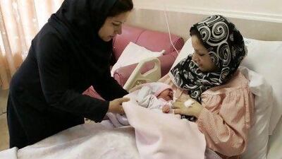 Iranian nurse Zahra Akbarzadeh (left) gives one-day-old girl Setayesh to her mother, Tayyebeh Sadat Bidaki, at the Mehr hospital, in Tehran. Iran is now slashing its birth control programmes.