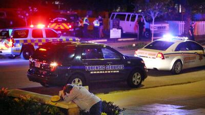 A man kneels across the street from where police gather outside the Emanuel AME church following a shooting on June 17, 2015 in Charleston, South Carolina. Wade Spees/The Post And Courier via Associated Press