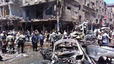 Syrians gather round after a bomb attack outside the Sayyida Zeinab shrine near Damascus on June 11, 2016. Sana via AP