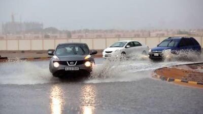 Motorists wade through a flooded round-about after rains in Al Harma, Ras Al Khaimah, yesterday. Most parts of the UAE experienced cloudy weather throughout the day before gusty winds bringing in low visibility and sporadic showers. Christopher Pike / The National
