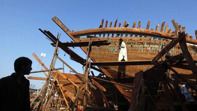 A worker is silhouetted as a carpenter works on a boat at a yard in Karachi's Fish Harbour. Akhtar Soomro / Reuters