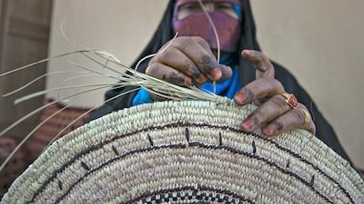Madyah al Rameethy weaves a traditional palm-leaf place mat. Silvia Razgova / The National