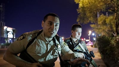 Police officers advise people to take cover near the scene of a shooting near the Mandalay Bay resort and casino on the Las Vegas Strip, Sunday, Oct. 1, 2017, in Las Vegas. (AP Photo/John Locher)
