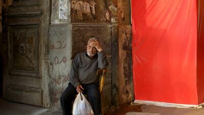 A man sits in front of an old building next to a shop that is being renovated.