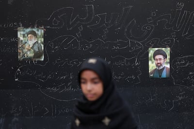 A mourner in front of pictures of late Iran's Supreme Leader Ayatollah Ali Khamenei and his son Mojtaba. Reuters