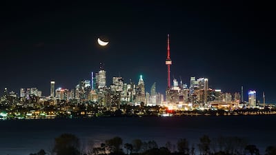 The moon rises behind the CN Tower and skyline in Toronto - a sight much of the world would like to go to bed to. Getty