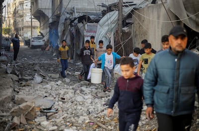 Palestinian children carry items as they walk at the site of Israeli strikes, amid the ongoing conflict between Israel and the Palestinian group Hamas, in Khan Younis in the southern Gaza Strip. Reuters