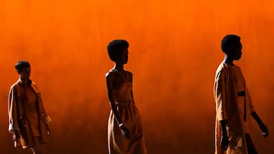 Models present creations against a backdrop of burnished yellow at the Hermes spring/summer 2022 show. AFP